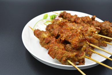 装在白色瓷盘里，香喷喷的烤好的羊肉串的特写