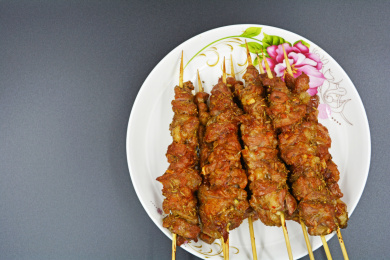 香喷喷的烤好的羊肉串装在白色带花纹的瓷盘里