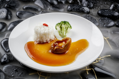 鲍汁捞饭摆放在干冰缭绕的黑色鹅卵石上