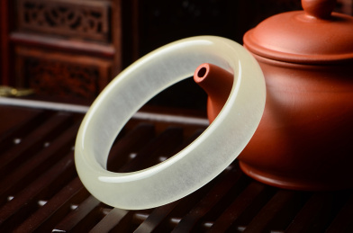 暗调复古中国风里靠在紫砂壶上的透明玉手镯