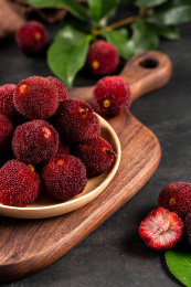 木板背景上的碟装新鲜杨梅局部特写