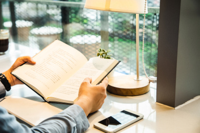 特写女性坐在落地窗台前打开一本书在阅读