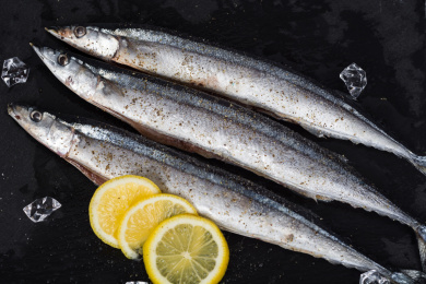 黑色石板上正在制作的日式盐烤秋刀鱼