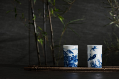 两个精致青花陶瓷笔筒在桌面上，在暗调背景中