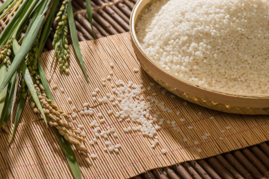 一堆白色大米放在竹子编织的盘子里在浅色的竹子餐垫上