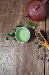 一个紫砂壶和装着茶水的汝窑茶杯放在旧木板上