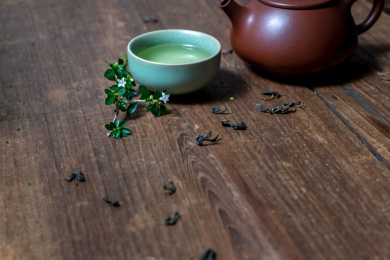 一个紫砂壶和装着茶水的汝窑茶杯放在旧木板上