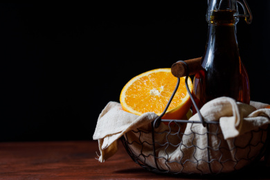 放在灰色铁篮子里的一瓶冰红茶和切开的西班牙甜橙