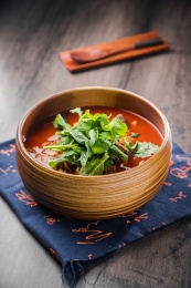 蓝色餐布上有一碗砂锅番茄汁牛杂汤锅