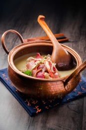 黑色餐布上的一口铜锅火腿炖柴鸡