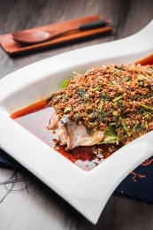 白色方形瓷盘里一条红油辣子蒸鲈鱼