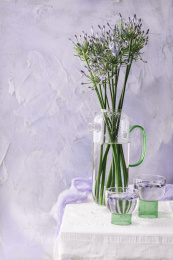 紫墙前摆桌上放着玻璃花瓶插着紫色的花