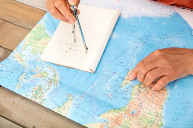 一只手在地图上指着确定的位置另一只手用圆规测量距离