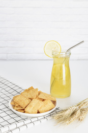 放在白色格子餐布上的小米锅巴和柠檬饮料麦穗