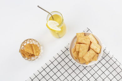 放在白色格子餐布上的小米锅巴和柠檬饮料