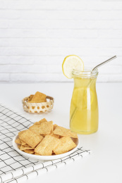 放在白色格子餐布上的小米锅巴和柠檬饮料