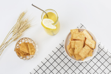 放在白色格子餐布上的小米锅巴和柠檬饮料麦穗