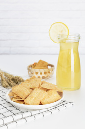 放在白色格子餐布上的小米锅巴和柠檬饮料麦穗