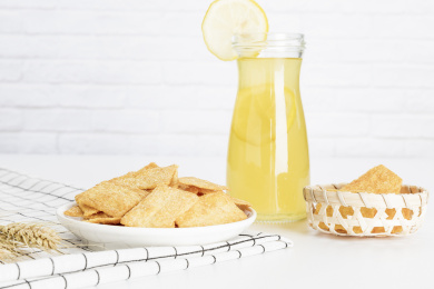 放在白色格子餐布上的小米锅巴和柠檬饮料麦穗