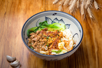 一碗放在木桌上的陕西西腊汁肉油泼面