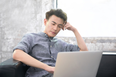 坐在沙发上使用电脑工作的商务男性