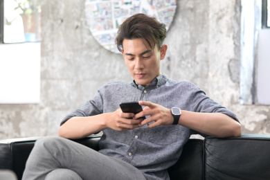 坐在沙发上玩手机的年轻中国男性
