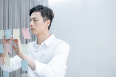 年轻男性在粘贴在墙上的便签纸上写字