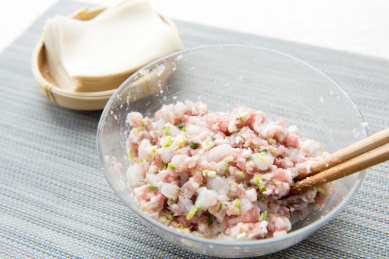 灰色餐垫上透明玻璃碗里的鲜虾馄饨馅