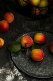 新鲜的带绿叶的杏放在暗黑铁盘子里