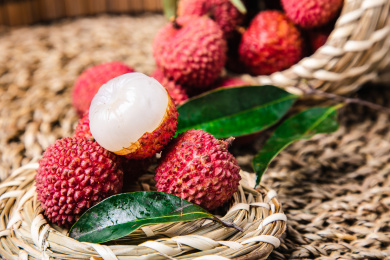 特写竹编的篮子里装满了带叶子的新鲜完整的和剥开一半的荔枝