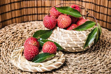 特写编织的碗里装着带有叶子的新鲜荔枝