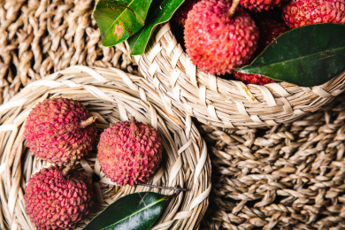 正上方视角特写编织的篮子里装着带叶子的多个新鲜荔枝