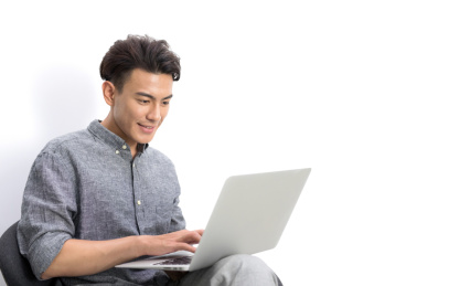 白背景前坐在椅子上高兴使用笔记本电脑的商务男士