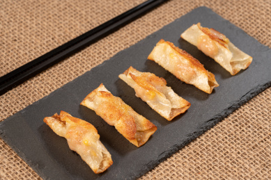 粗麻布上黑岩板上的煎饺和一旁的筷子