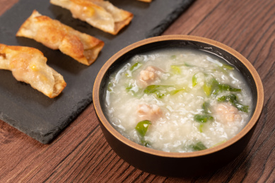 红褐色木板上桌面上的青菜瘦肉粥和煎饺