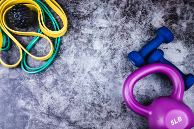 运动主题：正上方视角特写水泥质感地板上放着哑铃壶铃弹力绳和按摩球等运动器械