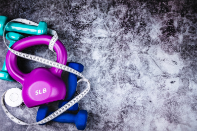 运动健康主题：正上方视角特写水泥质感地板上放着哑铃壶铃以及卷尺