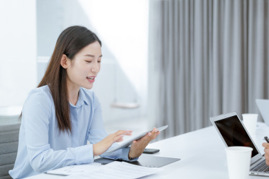 着职业装在办公室使用平板电脑的年轻女性