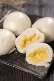 深色桌面摆放着传统广式甜点奶黄包