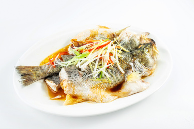 中国粤菜一碟清蒸鲈鱼在白背景上
