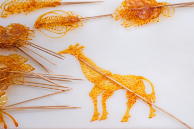 白色汉白玉石板上用黄色糖汁制作的中国民间传统糖画