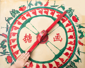 中国民间传统文化糖画木制手绘画板转盘上正在转糖画的小孩的手