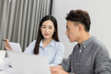 年轻的男员工和女员工在办公室内讨论工作上的相关问题