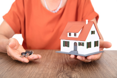 中国老太太一只手里端着小房子模型另一只手里拿着新房钥匙