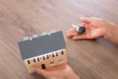 老人一手端着小房子模型另一只手拿着新房钥匙