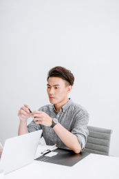 穿灰色衬衣坐在办公桌前工作的年轻男士