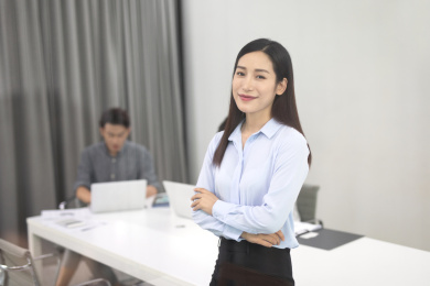 会议室内靠在会议桌上看着镜头微笑的年轻女士