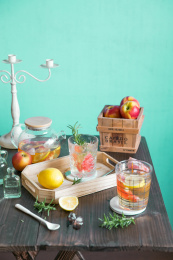 木质桌子上摆放玻璃杯盛放的夏日水果茶、木质托盘中放有水果