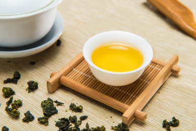 中国传统绿茶和白色瓷器茶杯在木质茶盘上泡茶，特写画面