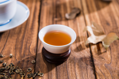 散装的茶叶和一个白色瓷器茶杯在旧桌面上